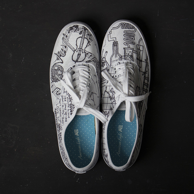 White Converse shoes with black illustrations of assorted objects (top view)