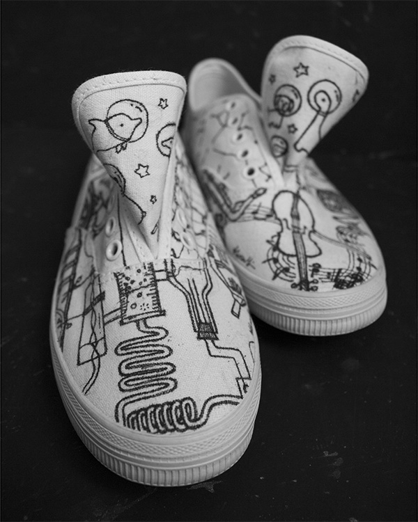 White Converse shoes with black illustrations (front view)