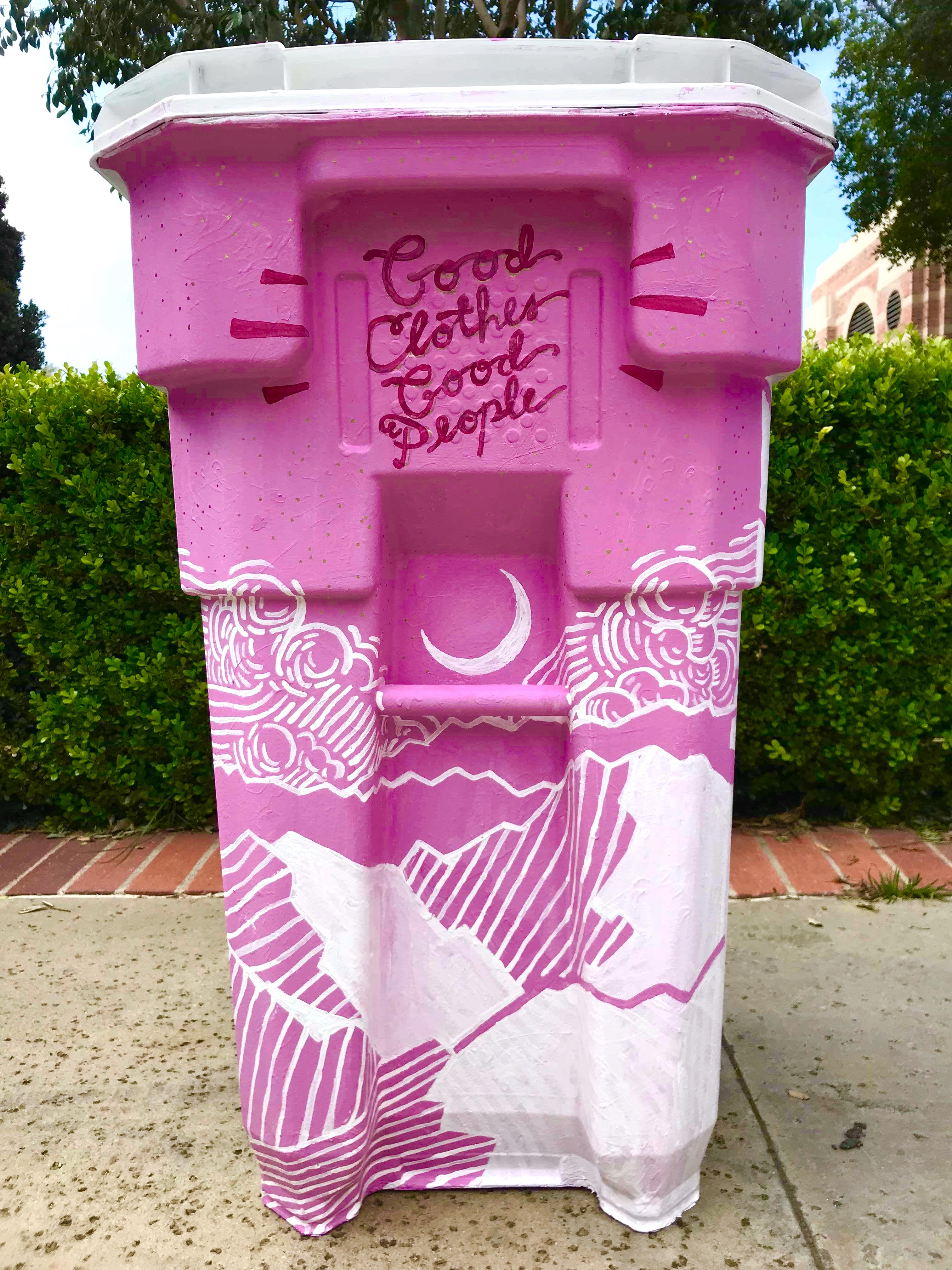 Trash can painted in pink with magenta cursive text saying Good Clothes Good People