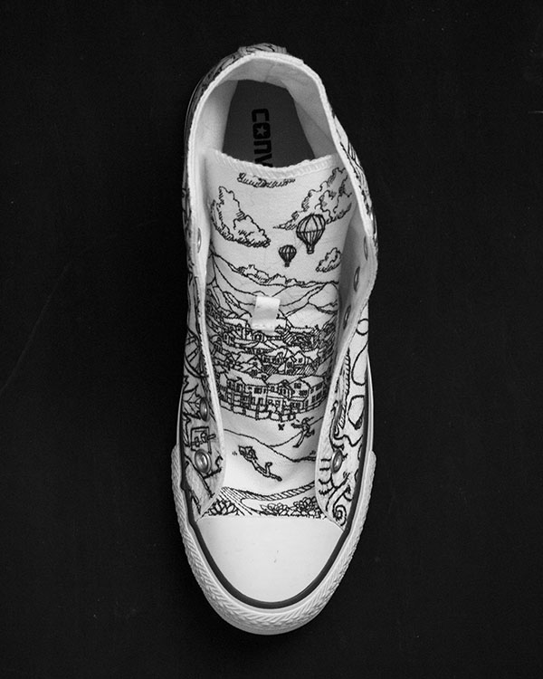 White Converse shoe with black and pink illustrations of hands (top view)