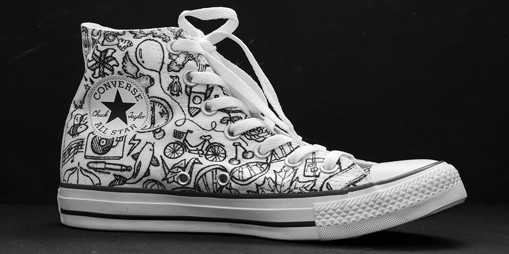 White Converse shoe with black illustrations of assorted objects  (side view)