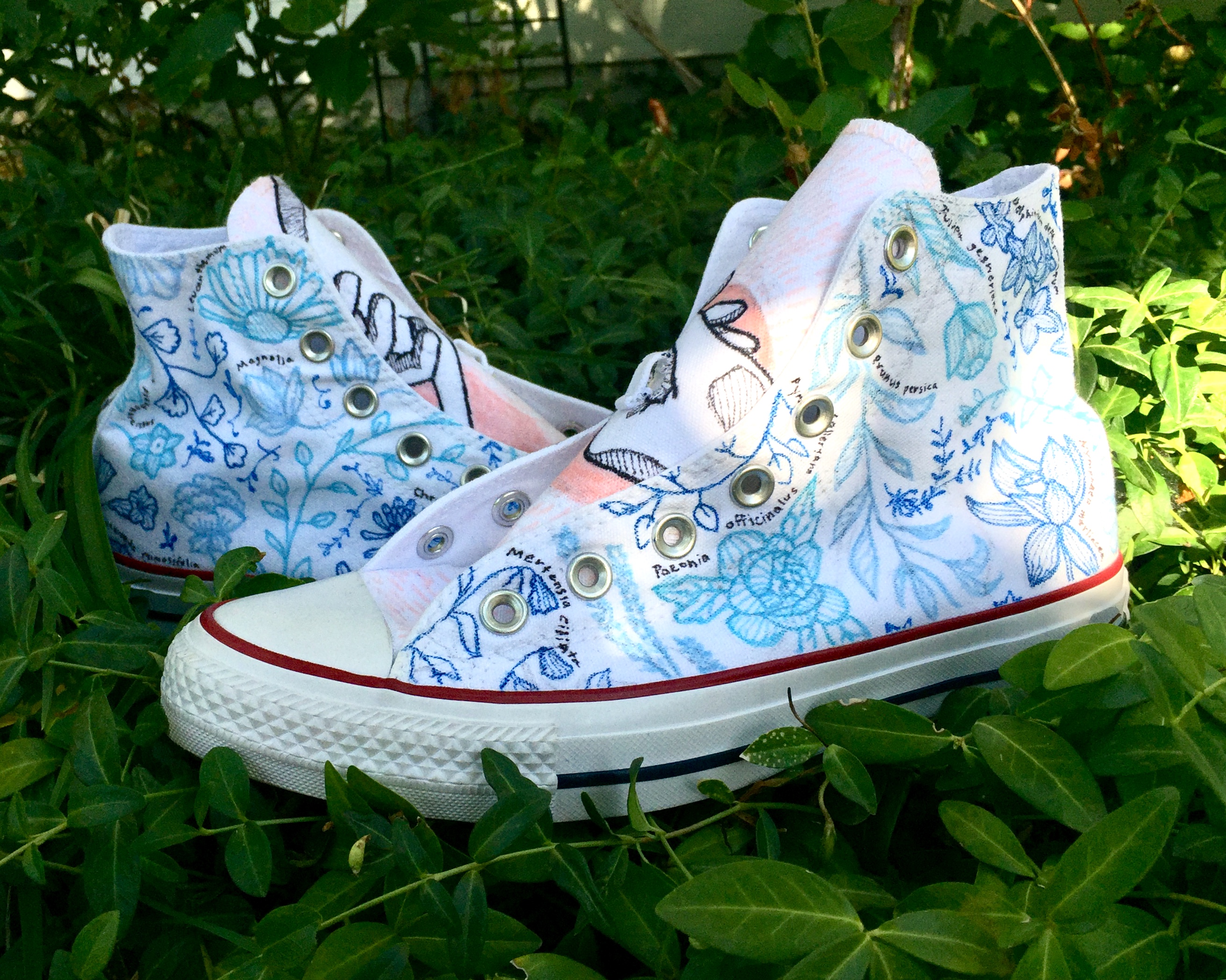 White Converse shoes with blue illustrations of flowers and leaves (side view)