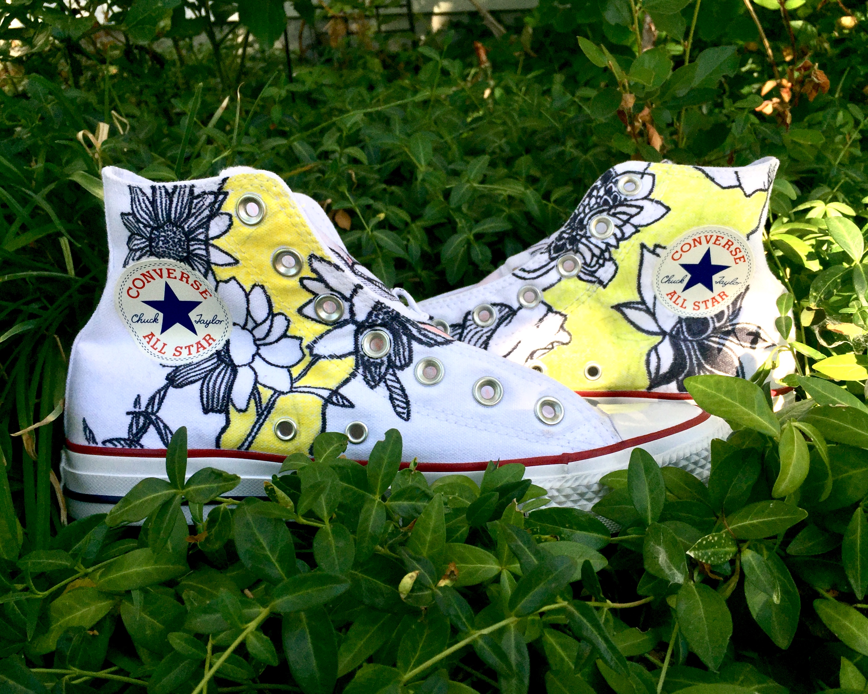 White Converse shoes with illustrations of yellow and black sunflowers and lilies (side view)